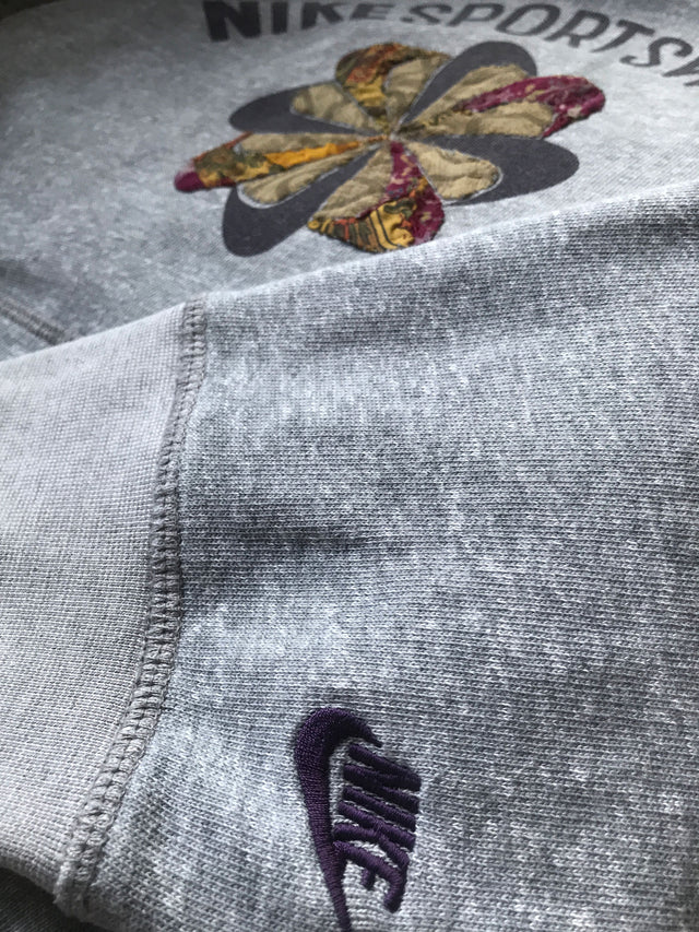 Embroidered Nike logo on sleeve with patched pinwheel logo in background